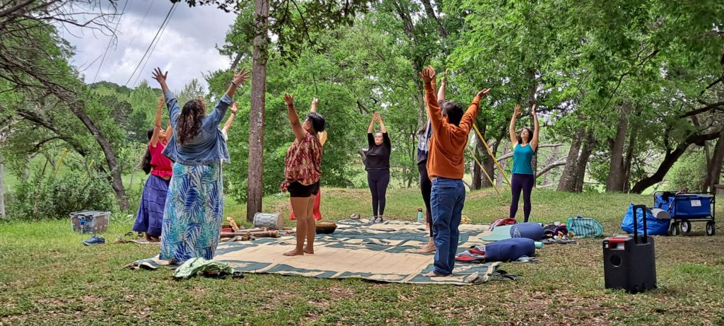 Picture of a Florecemos retreat with participants standing outside with their arms raised. 