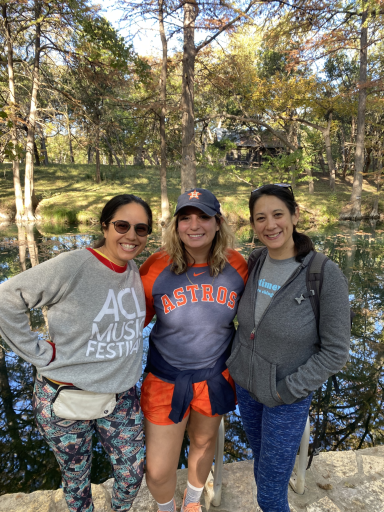 Three 2022 Florecemos circle members at their closing retreat. Smiling in a group picture outside in front of a creek.